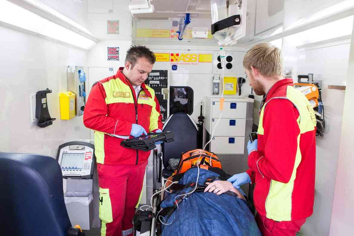 Zwei Notfallsanittäter behandeln einen Patienten im Rettungswagen.