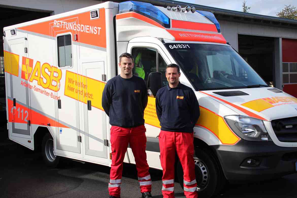 Zwei Mitarbeiter der Rettungswache Nörten-Hardenberg vor dem Rettungswagen.